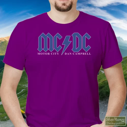 Detroit Lions Mcdc Motor City Hooded Dan Campbell Acdc Men’s T Shirt – Purple Front View On Light Wood Background Men's Detroit Lions Mcdc Motor City Hooded Dan Campbell Acdc T Shirt In Purple, Front View On Light Wood Background