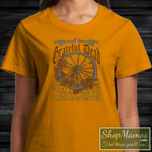 Grateful Dead 1994 The Wheel Summer Tour Bound To Cover Just A Little More Ground Women’s T Shirt – Orange Front View On Dark Wood Background Women's Grateful Dead 1994 The Wheel Summer Tour Bound To Cover Just A Little More Ground T Shirt In Orange, Front View On Dark Wood Background