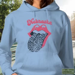 Leopard Tongue Rolling Stones Style Nebraska Huskers Shirt White 8 Women's Leopard Tongue Rolling Stones Style Nebraska Huskers White Hoodie In Light Blue, Front View On Dark Wood Background