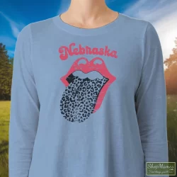 Leopard Tongue Rolling Stones Style Nebraska Huskers Shirt White 1 Women's Leopard Tongue Rolling Stones Style Nebraska Huskers White Long Sleeve In Light Blue, Front View On Dark Wood Background