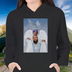Two Angels Tupac Shakur And Nipsey Hussle Shirt 5 Women's Two Angels Tupac Shakur And Nipsey Hussle Hoodie In Black, Front View On Light Wood Background